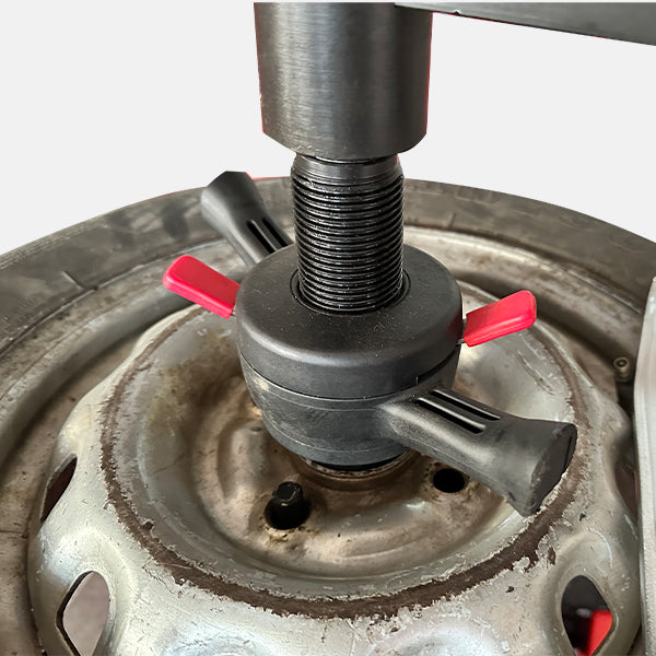 Close-up of a tire changer tool in action on a tire.